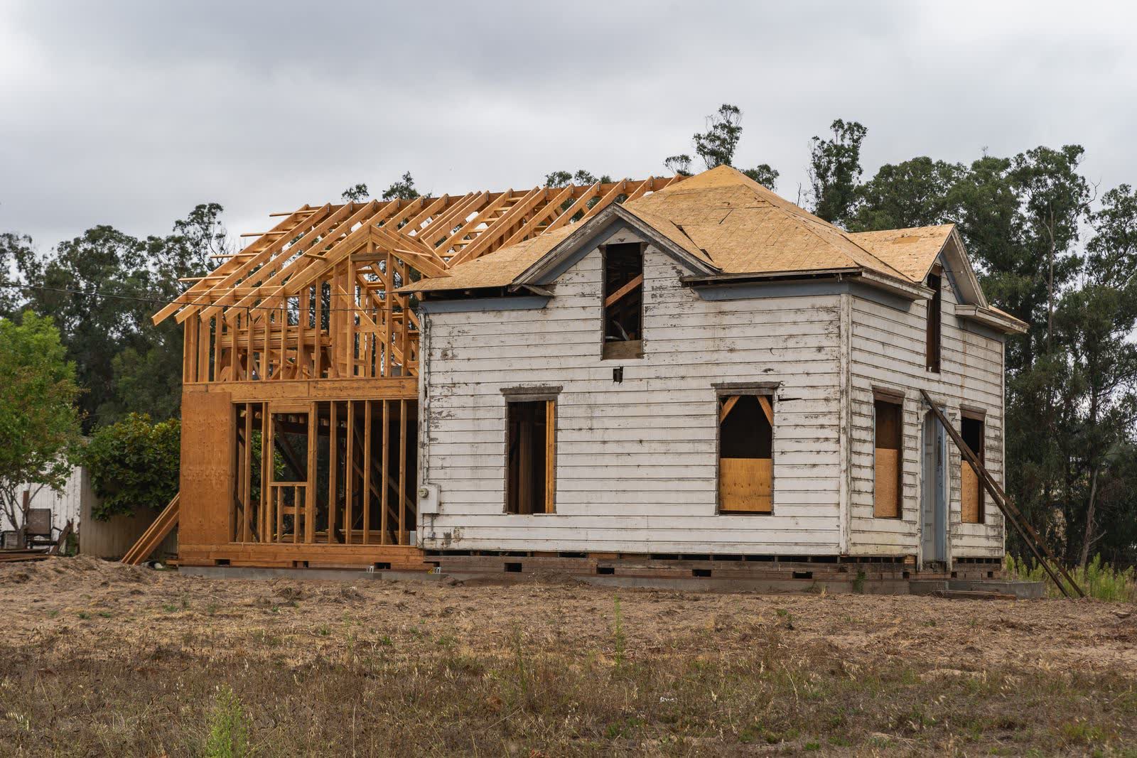 A room addition framed in fresh lumber and joined onto the side of an existing clapboard house