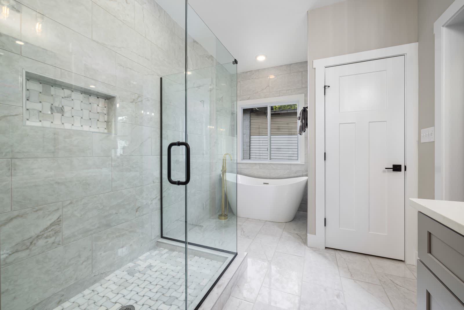 A finished bathroom remodel with a frameless glass walk-in shower and marble-look tile