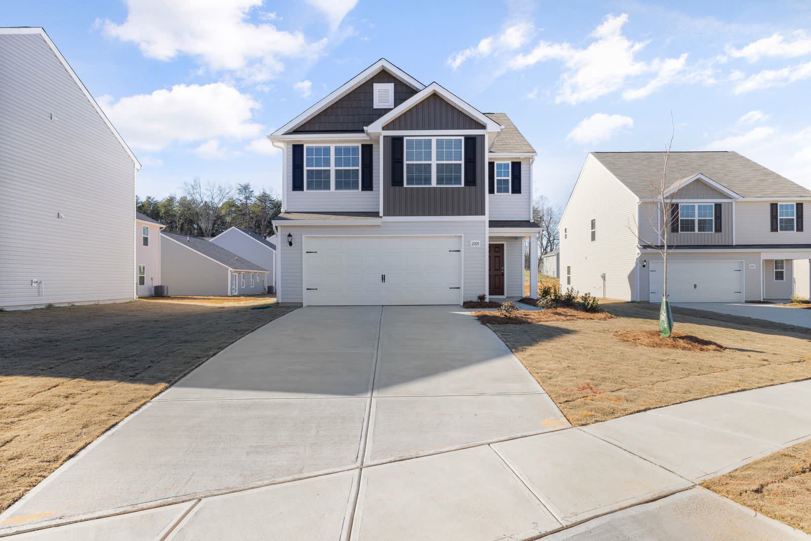 A newly finished pale concrete driveway with crisp control joints running up to a two-car garage