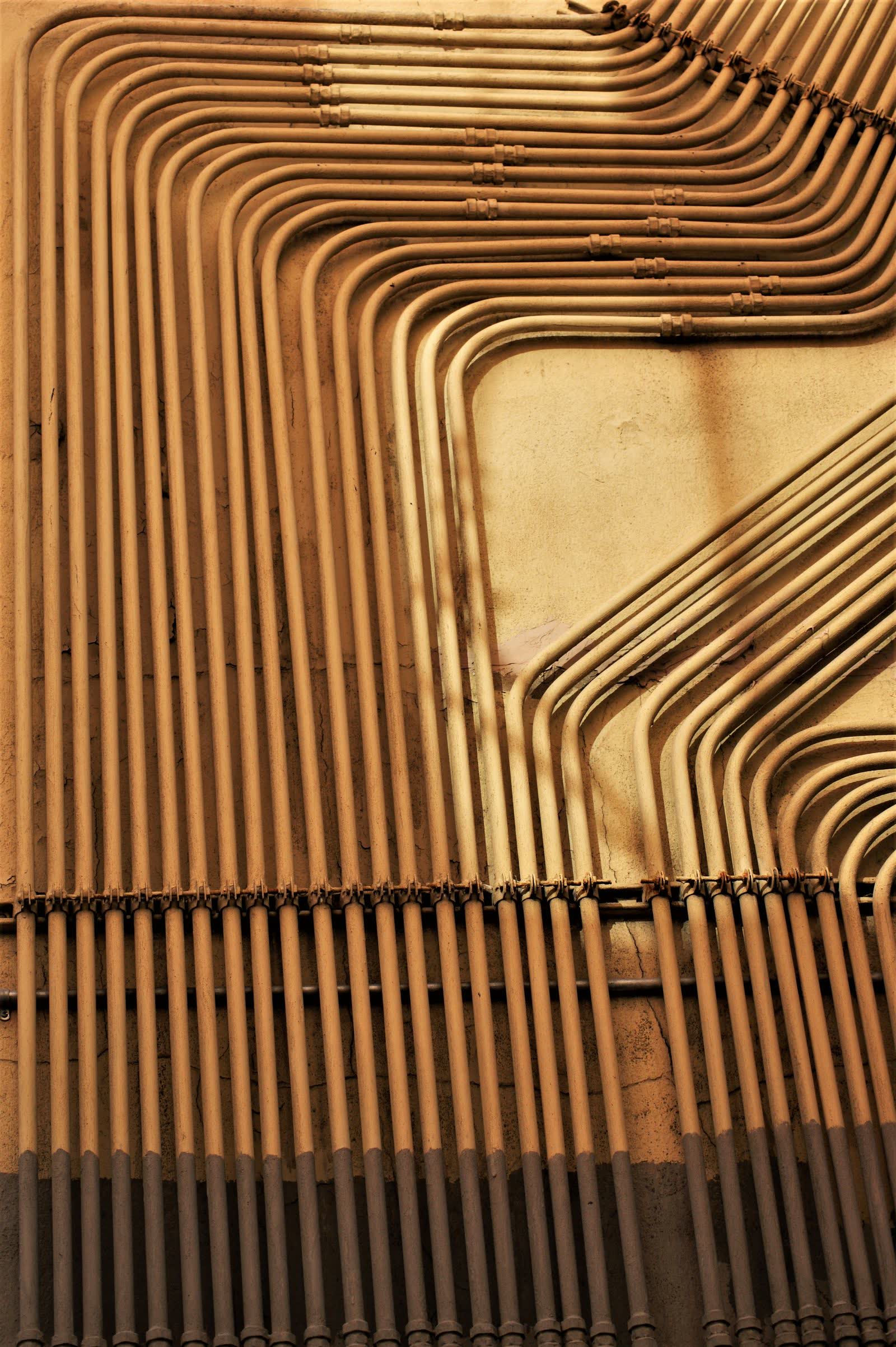 Rows of neatly bent copper plumbing pipe running in parallel across a wall